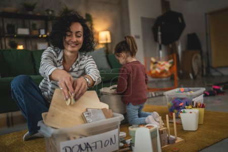 Téléchargez les photos : Mère et fille tout-petit à la maison choisissent des jouets pour le don de charité - en image libre de droit