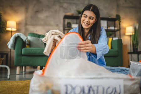 Photo for One woman caucasian adult at home choose clothes for charity donation - Royalty Free Image
