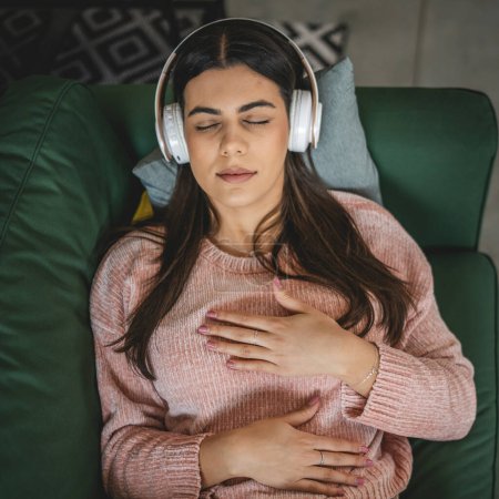 Photo for One woman adult caucasian female millennial using headphones for online guided meditation practicing mindfulness yoga with eyes closed at home real people self care concept copy space - Royalty Free Image