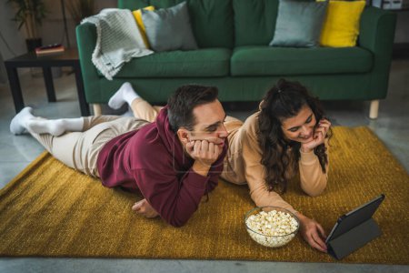 Téléchargez les photos : Couple homme et femme à la maison regarder la vidéo du film sur tablette numérique - en image libre de droit