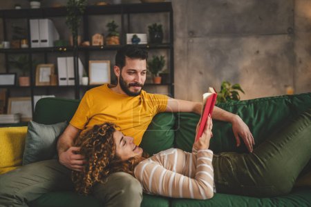 Photo for Man and woman caucasian adult couple read books at home on sofa bed - Royalty Free Image