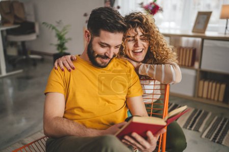 Téléchargez les photos : Homme et femme caucasien adulte couple lire des livres à la maison - en image libre de droit
