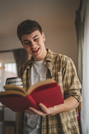 Foto de Joven caucásico adolescente leer libro estudio en casa educación concepto - Imagen libre de derechos