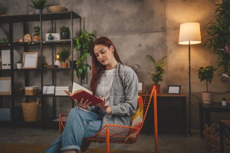 Photo for Young adult woman one female student read book or study at home red hair copy space - Royalty Free Image