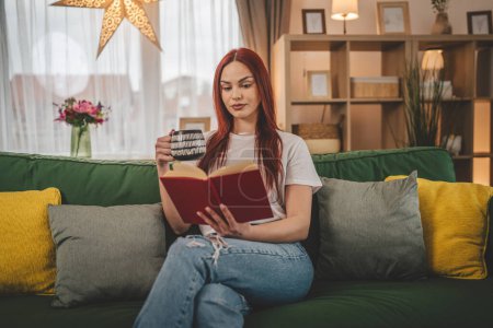 Foto de Mujer adulta joven una estudiante femenina leer libro o estudiar en casa rojo espacio de copia de pelo - Imagen libre de derechos