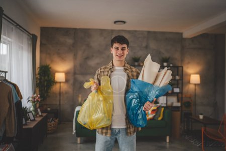 Téléchargez les photos : Un homme jeune adulte recycler à la maison trier les déchets de papier plastique et de verre - en image libre de droit