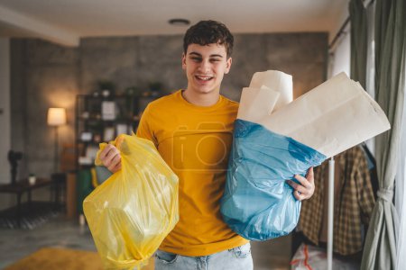 Foto de Un hombre joven adulto recicla en casa clasificar residuos de papel plástico y vidrio - Imagen libre de derechos