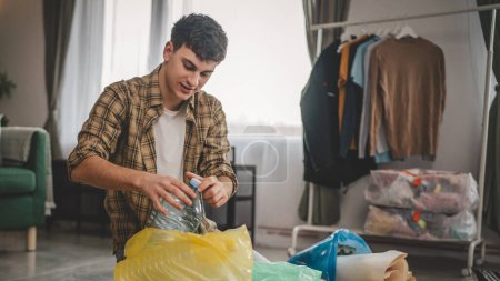 Foto de Un hombre joven adulto recicla en casa clasificar residuos de papel plástico y vidrio - Imagen libre de derechos