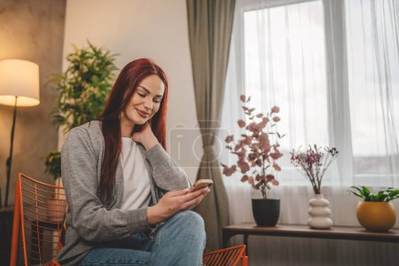 Foto de Mujer joven en el hogar utilizar el teléfono móvil SMS mensajes de texto o navegar por Internet - Imagen libre de derechos