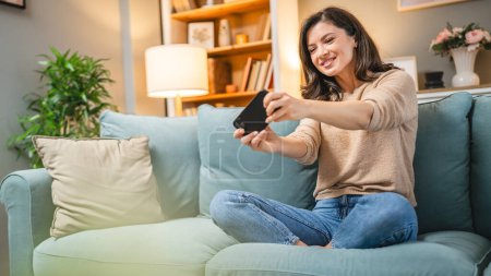 Foto de Una mujer caucásica adulta se sienta en casa feliz sonrisa jugar videojuegos actividad de ocio divertirse celebrar el uso del teléfono móvil teléfono inteligente divertirse en línea - Imagen libre de derechos