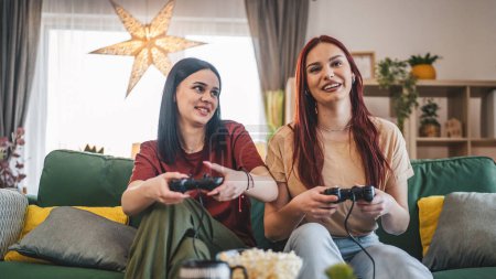Téléchargez les photos : Deux jeunes femmes caucasiennes amis ou sœurs jouent jeu vidéo console - en image libre de droit