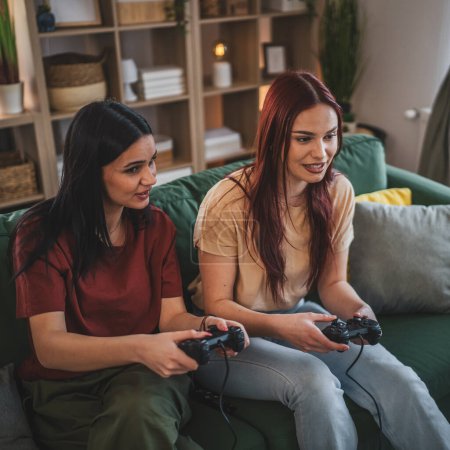 Foto de Dos jóvenes mujeres caucásicas amigas o hermanas juegan videojuego de consola - Imagen libre de derechos