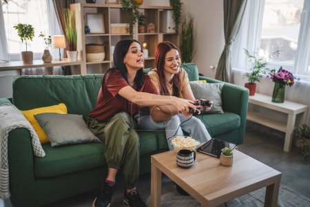Téléchargez les photos : Deux jeunes femmes caucasiennes amis ou sœurs jouent jeu vidéo console - en image libre de droit