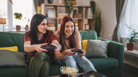 Foto de Dos jóvenes mujeres caucásicas amigas o hermanas juegan videojuego de consola - Imagen libre de derechos