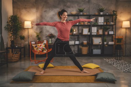 Téléchargez les photos : Femme caucasienne pratique le yoga sur tapis dans le salon à la maison - en image libre de droit