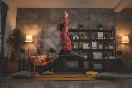 Téléchargez les photos : Femme caucasienne pratique le yoga sur tapis dans le salon à la maison - en image libre de droit