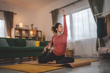 Foto de Mujer caucásica practican yoga sobre estera en salón en casa - Imagen libre de derechos