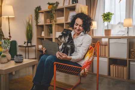 Foto de Retrato adulto caucásico mujer uso digital tableta con mascota perro en casa - Imagen libre de derechos