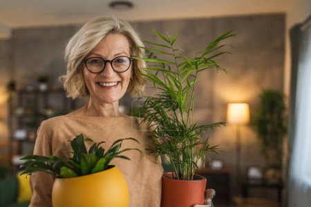 Téléchargez les photos : Une femme fleuriste prendre soin de cultiver des plantes à la maison - en image libre de droit