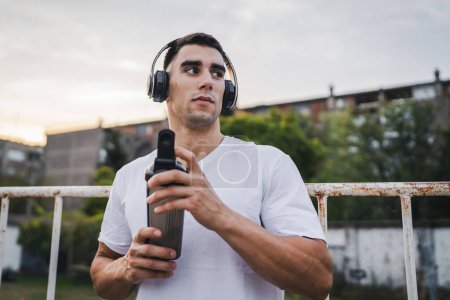 Photo for One caucasian man young male athlete take a brake during outdoor training outdoor hold supplement shaker in hand happy confident strong copy space - Royalty Free Image
