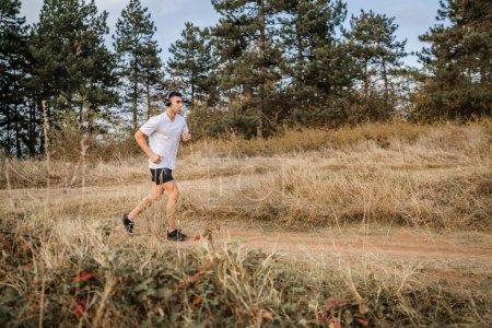 Photo for One man young caucasian male athlete running in nature outdoor on dirt road jogging in autumn or summer day sport fitness and recreation healthy lifestyle concept real people copy space - Royalty Free Image