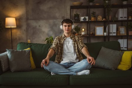 Téléchargez les photos : Un adolescent faisant méditation guidée yoga pratique de l'auto-soin à la maison - en image libre de droit