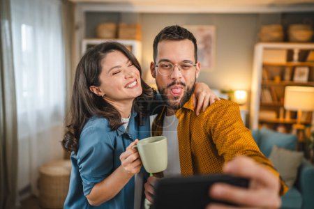 Foto de Autorretrato selfie de feliz pareja marido y mujer novio y novia o hermano y hermana feliz sonrisa en casa - Imagen libre de derechos