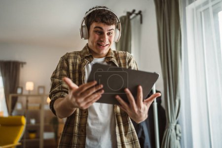 Téléchargez les photos : Homme caucasien mâle à la maison regarder film vidéo en ligne utiliser tablette numérique - en image libre de droit
