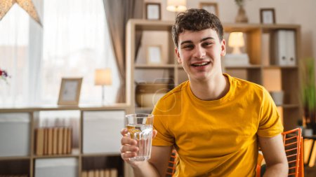Téléchargez les photos : Homme jeune caucasien mâle tenir verre d'eau à la maison - en image libre de droit