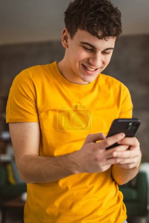 Téléchargez les photos : Un homme caucasien mâle adolescent garçon utiliser téléphone mobile smartphone sms - en image libre de droit