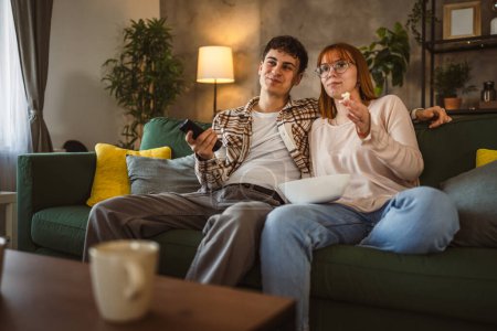 Téléchargez les photos : Couple caucasien homme et femme assis à la maison sur canapé-lit regarder la télévision film - en image libre de droit