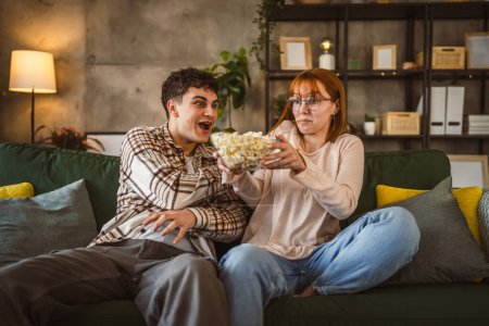 Téléchargez les photos : Couple caucasien homme et femme assis à la maison sur canapé-lit regarder la télévision film - en image libre de droit