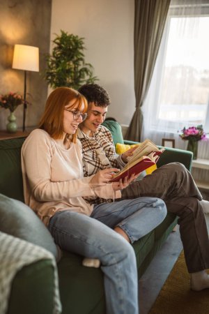 Photo for Man and woman caucasian adult couple read books at home on sofa bed - Royalty Free Image