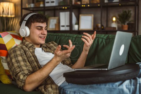Téléchargez les photos : Un adolescent caucasien utilise un ordinateur portable avoir un appel vidéo à la maison - en image libre de droit