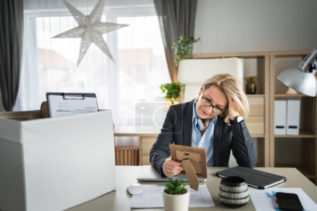 mature caucasian woman businesswoman at the office lost her job packing personal items things in box being fired from work