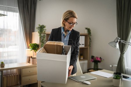 Photo for Mature caucasian woman businesswoman at the office lost her job packing personal items things in box being fired from work - Royalty Free Image