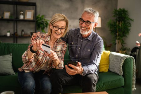 Photo for Mature or senior couple husband and wife shopping online sit at home - Royalty Free Image