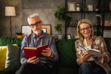 Téléchargez les photos : Mature couple âgé homme et femme mari et femme lire le livre à la maison - en image libre de droit