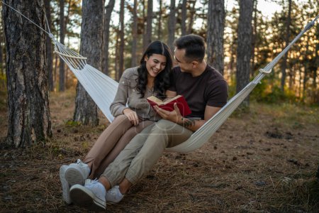 Photo for Man and woman young adult couple in nature hold and read book in love - Royalty Free Image
