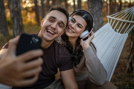 Téléchargez les photos : Homme et femme jeune couple adulte dans la nature prendre autoportrait photo selfie ugc utiliser téléphone mobile smartphone ou faire un appel vidéo - en image libre de droit
