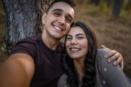 Photo for Man and woman young adult couple in nature take self portrait photo selfie ugc use mobile phone smartphone or make a video call - Royalty Free Image