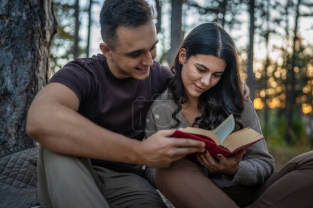 Téléchargez les photos : Homme et femme jeune couple adulte dans la nature tenir et lire livre en amour - en image libre de droit