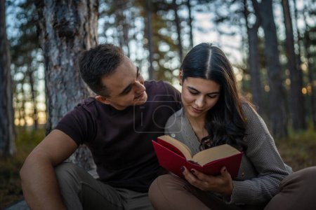 Téléchargez les photos : Homme et femme jeune couple adulte dans la nature tenir et lire livre en amour - en image libre de droit