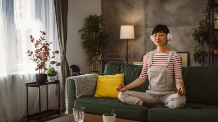 Téléchargez les photos : Femme japonaise mature pratique la méditation guidée manifestation à la maison - en image libre de droit
