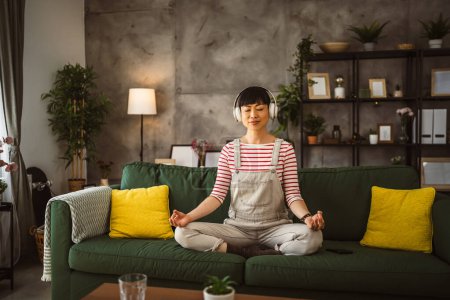 Téléchargez les photos : Femme japonaise mature pratique la méditation guidée manifestation à la maison - en image libre de droit