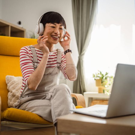 Photo for Woman Japanese female sit at home use laptop computer to watch movie or have video call - Royalty Free Image