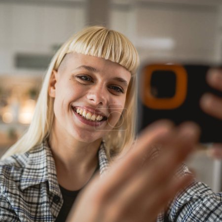 Téléchargez les photos : Adulte femme prendre un selfie photo autoportrait à la maison heureux positif - en image libre de droit