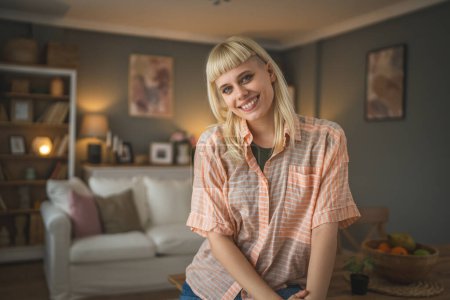 Téléchargez les photos : Portrait de jeune femme blonde caucasienne au salon à la maison heureux positif - en image libre de droit