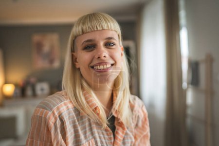 Téléchargez les photos : Portrait de jeune femme blonde caucasienne au salon à la maison heureux positif - en image libre de droit