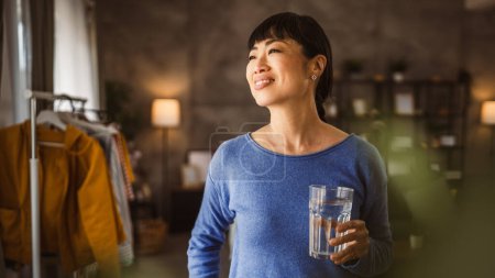Téléchargez les photos : Portrait of one japanese mature woman with glass of water at home - en image libre de droit